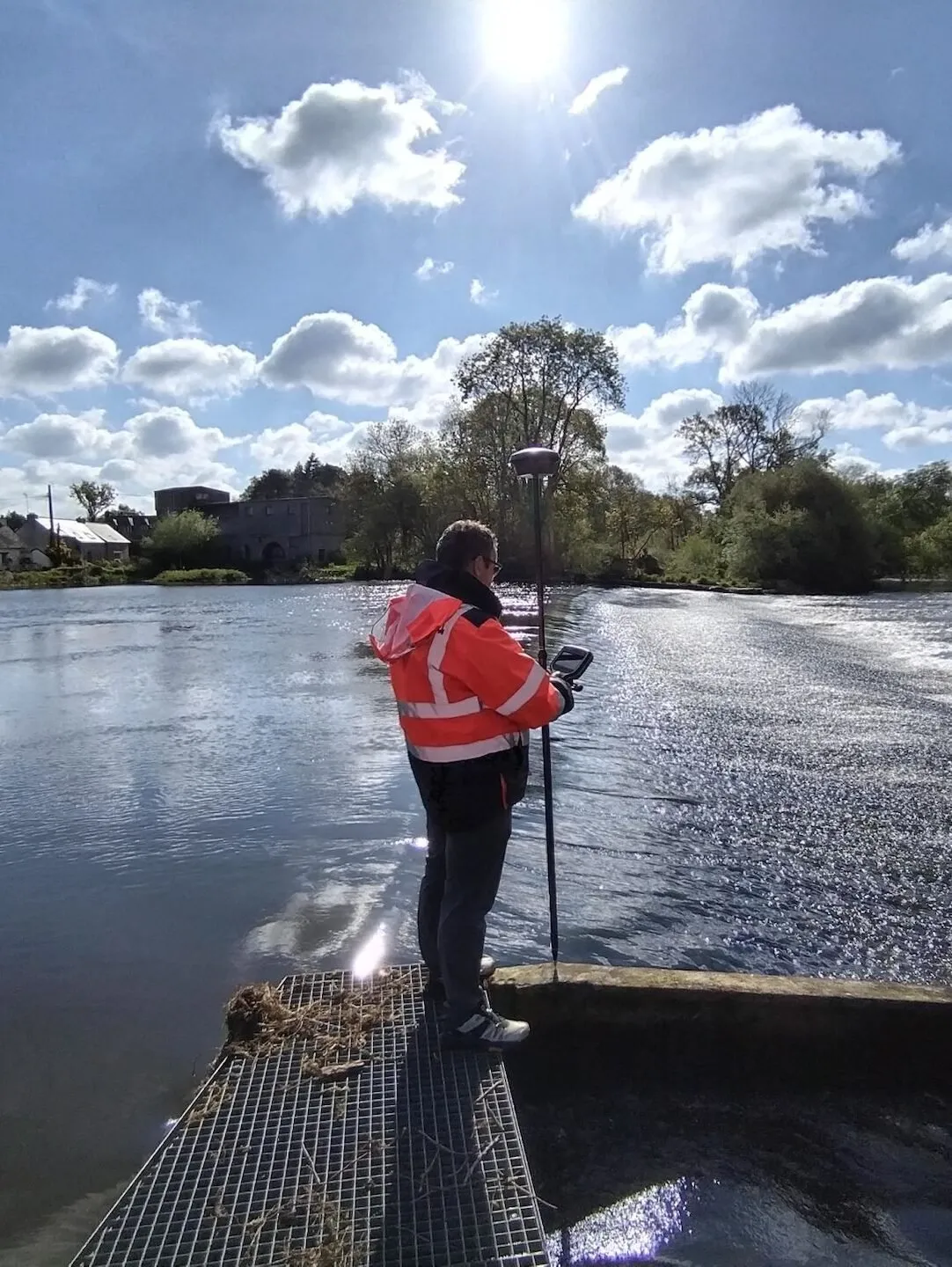 Géomètre-topographe en relevé GNSS au bord d’une rivière